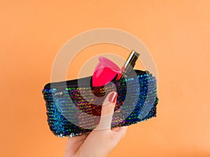 Pink menstrual cup in female sequin pochette bag