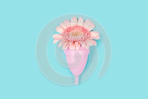 Pink menstrual cup and a flower on blue background