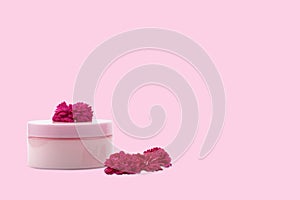 Pink mocap jar for cream, balm, lotion and a small pink-Red roses on a pink background. Isolated, closeup