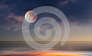 Pink moon  at sea  on blue starry sky at gold yellow sunset natire seascape photo