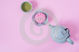 Pink mooncake, blue teapot, cup of green tea on a pink background. Chinese mid-autumn festival food