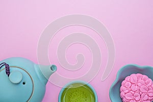 Pink mooncake, blue teapot, cup of green tea on a pink background. Chinese mid-autumn festival food