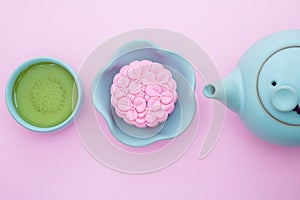 Pink mooncake, blue teapot, cup of green tea on a pink background. Chinese mid-autumn festival food