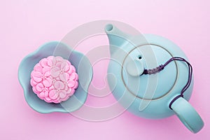 Pink mooncake, blue teapot, cup of green tea on a pink background. Chinese mid-autumn festival food