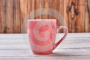 Pink mug on wooden background.