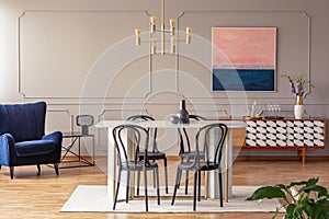 Pink and navy blue abstract painting on a gray wall with molding in an elegant dining and living room