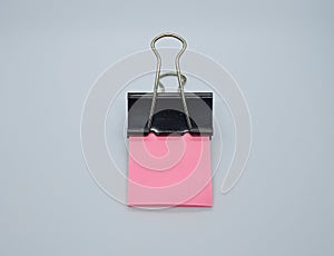 Pink note paper with black binder clip. Binder clip and stack of pink note paper