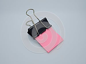 Pink note paper with black binder clip. Binder clip and stack of pink note paper