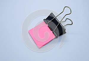 Pink note paper with black binder clip. Binder clip and stack of pink note paper