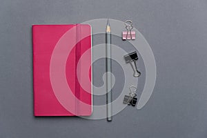 Pink notebook with grey pencil and paper clip for business or school background