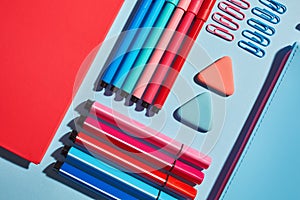 Pink notebook next to markers on a blue background