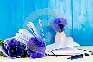 Pink notebook, pen and blue Anemone flowers. Concept of planning