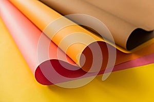 Pink and orange papers rolled together over yellow color paper. Papers for creative craft and design in school