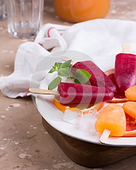 Pink and orange popsicle on grey stone background.