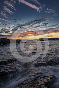 Pink and orange sunset over coastal rocks and sea