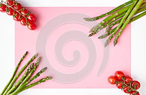 Pink paper background with white borders decorated with asparagus stems and branches of cherry tomatoes in the corners.