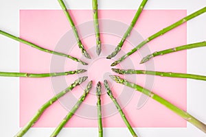 Pink paper background with white borders decorated with asparagus stems like rays of the sun.