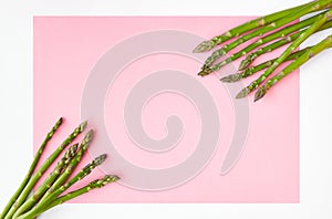 Pink paper background with white borders decorated with asparagus stems in the two opposite corners.