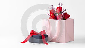 Pink paper bag with rose bouquet and black gift box with bow on white background