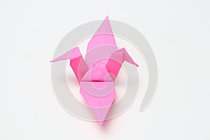 A pink paper bird, the result of folded origami art.