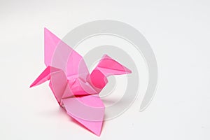 A pink paper bird, the result of folded origami art.