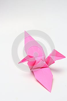 A pink paper bird, the result of folded origami art.