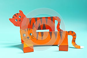 Pink paper hare on an orange cube on a light background.