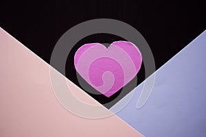 Pink paper heart chape with blue and pink paper on black background. photo