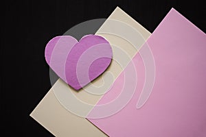 Pink paper heart chape on yellow and pink paper with black background. photo