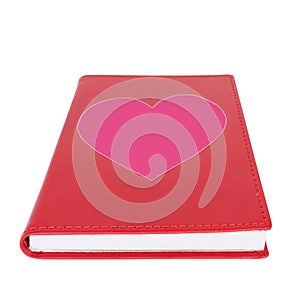 Pink paper heart on red book isolated on white