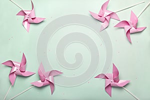 Pink paper spinners on blue background. Kids toys colorful pinwheels on celebration party background. Top view, flat lay