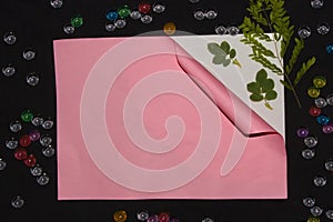 pink paper unrolling under it white paper on a piece of green leaf on a black background creative art nautral design photo