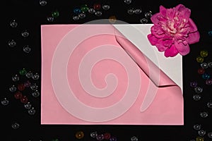 pink paper unrolling under it white paper with pink flower on a black background creative art romantic design