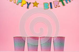 Pink party cups with happy birthday garland on pink background