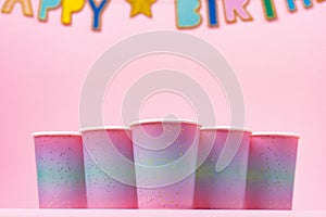 Pink party cups with happy birthday garland on pink background