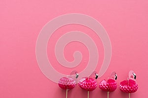 pink party toothpicks in a shape of flamingo on a pink background. origami