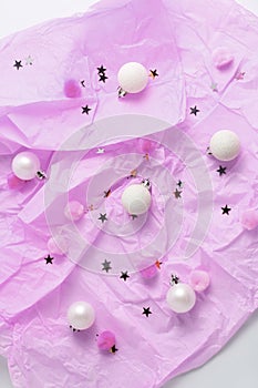 pink pastel background. Christmas balls, pompons and glitter stars.