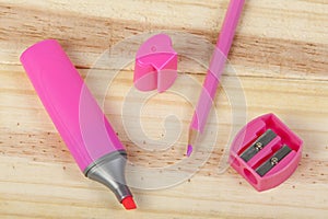 Pink pencil, highlighter and pencil sharpener on wooden desk