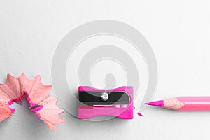 Pink pencil, sharpener and shavings on white background, flat lay. Space for text
