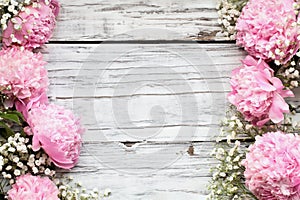 Pink Peonies and Babys Breath Flowers over a White Wooden Background photo