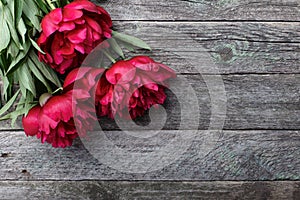 Pink peonies flowers on rustic wooden background. Place for text, top view