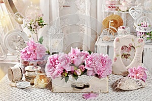 Pink peonies in old wooden drawer on the table in shabby chic style interior