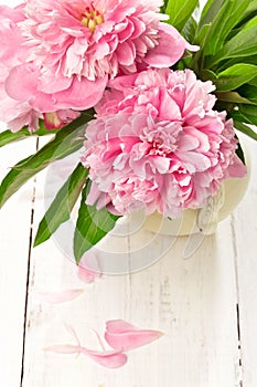 Pink peonies in retro vase on wooden table