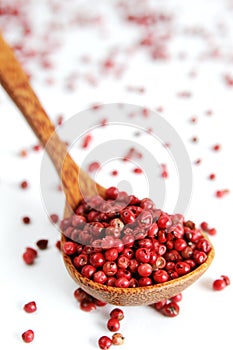 Pink pepper balls in a wooden spoon