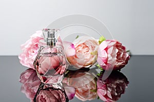 Pink perfume bottle with flowers on black and white background. Perfumery, cosmetics, fragrance collection