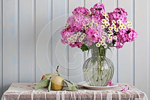 Pink phlox and daisies in a potbellied vase and apples. Rural still life, summer composition