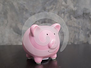 Pink piggy bank on black cement wall background, Saving money for future plan and retirement fund concept