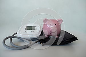 Pink piggy bank with blood pressure monitor on white background, Saving money for future plan and retirement fund concept