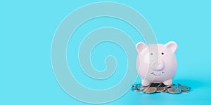 Pink piggy bank on blue background with copy space