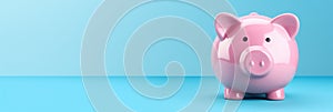 Pink piggy bank on blue background with copy space. Money savings concept. Banner 3:1